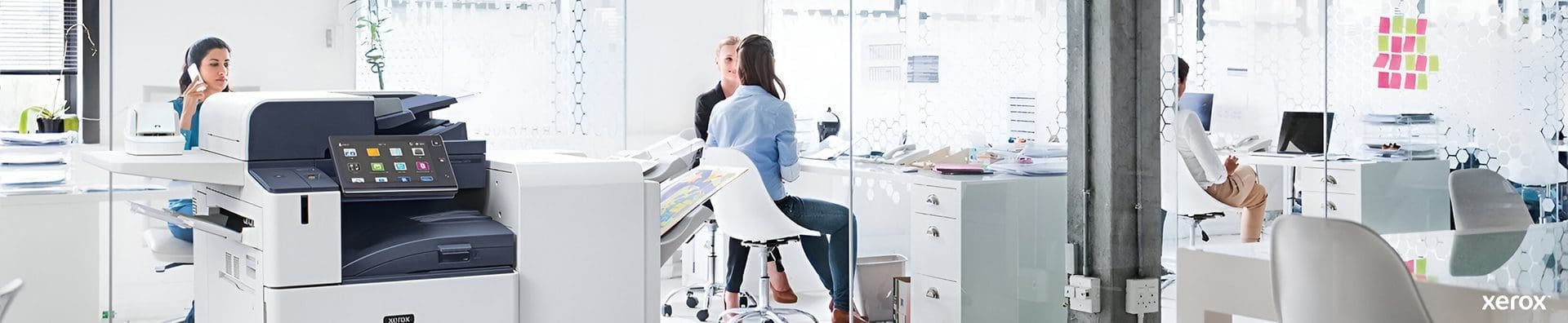 Una oficina espaciosa con una impresora Xerox® y una computadora sobre un escritorio, que muestra un entorno de trabajo profesional.
